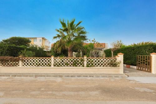 una cerca con una palmera delante de una casa en Appartamenti delle rose by BarbarHouse, en Torre Lapillo