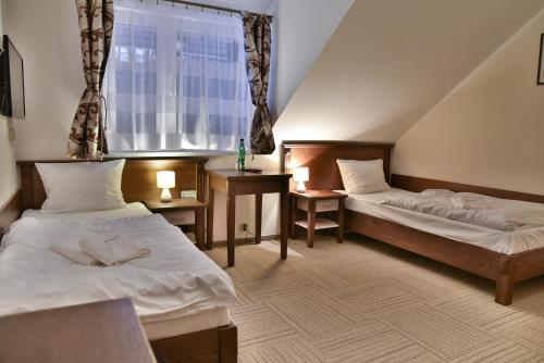 a hotel room with two beds and a window at Pensjonat Leśniczówka in Słubice