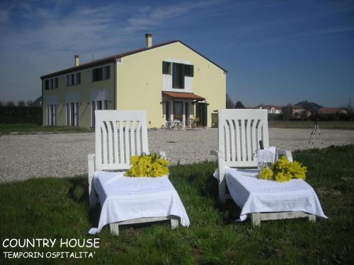 - deux chaises blanches avec des fleurs devant une maison dans l'établissement Temporin Ospitalità, à Monselice