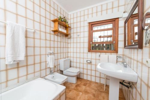 een badkamer met een wastafel, een toilet en een raam bij Finca SA VINYETA in Selva