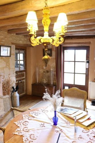 a dining room with a table and a chandelier at Le bourgis in La Chapelle-Montligeon