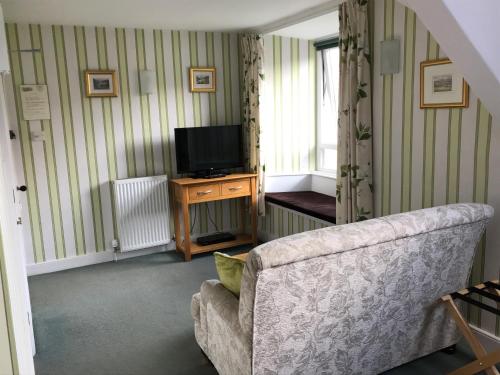 a living room with a couch and a television at Crow How Country Guest House in Ambleside