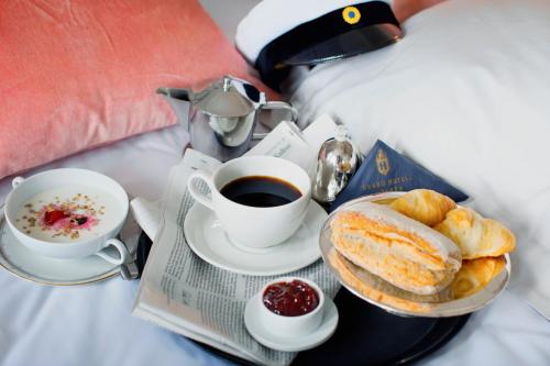 a breakfast tray with coffee and pastries on a bed at Grand Hotell Hörnan in Uppsala
