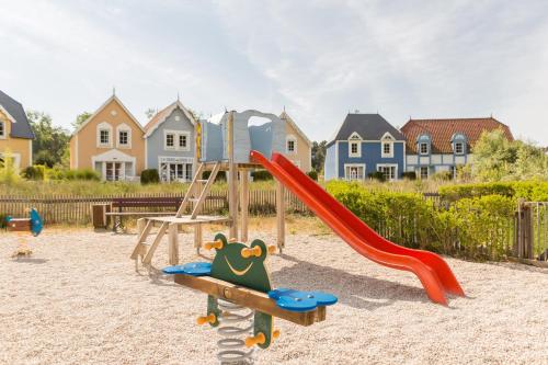 a playground with a slide in front of houses at Village Pierre & Vacances Belle Dune in Fort-Mahon-Plage