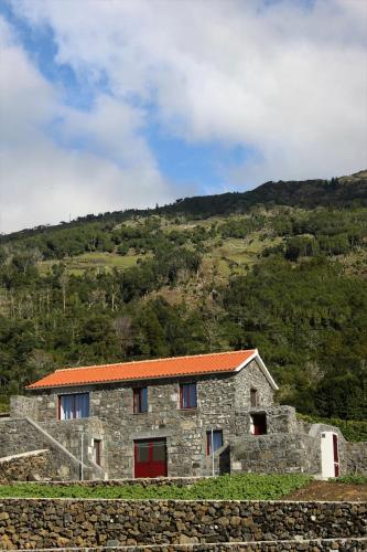 a stone house with an orange roof on a hill at Melo's Place in Madalena