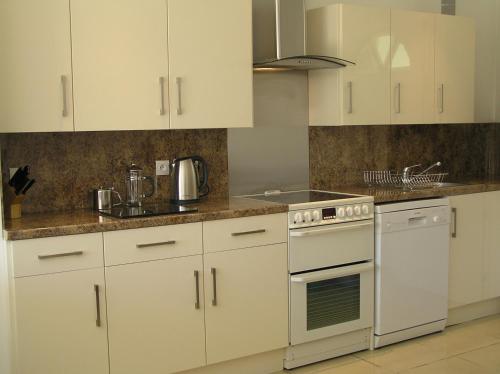 une cuisine avec des armoires blanches et un four à plaques de cuisson dans l'établissement Les Lavandes, à Étaules