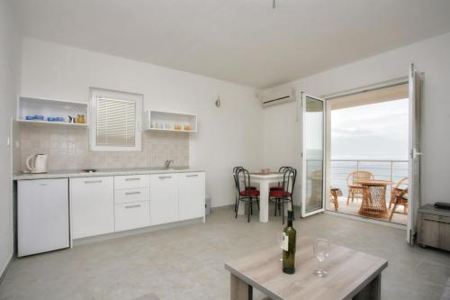 a kitchen with white cabinets and a table with a window at Boka Apartmani in Bijela