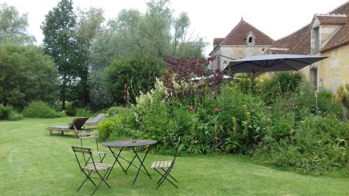 a garden with a table and chairs and an umbrella at Le bourgis in La Chapelle-Montligeon