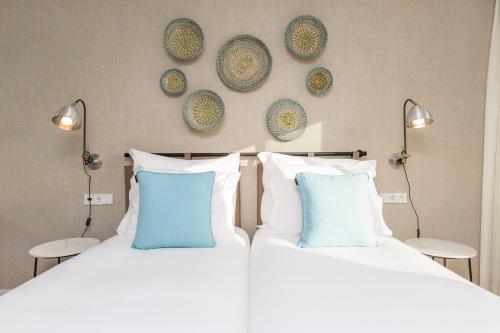 two beds with blue pillows and plates on the wall at Santiago Hotel in Santiago do Cacém