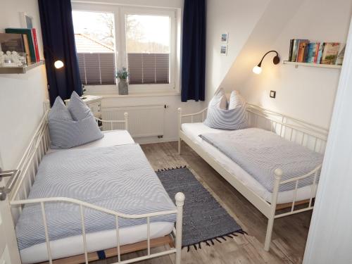 two beds in a small room with a window at Kranichnest in Hohwacht