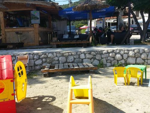 a group of yellow chairs and tables and a stone wall at Apartmani Premijer-Rab in Supetarska Draga