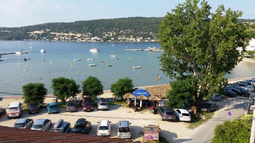 a parking lot with parked cars and boats in the water at Apartmani Premijer-Rab in Supetarska Draga