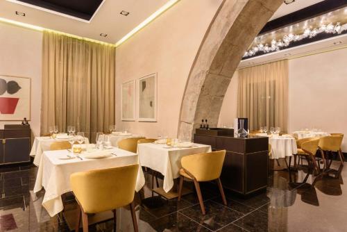a restaurant with white tables and yellow chairs at Áurea Museum by Eurostars Hotel Company in Lisbon