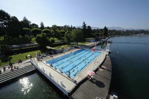 a large swimming pool on the side of a lake at Logis Hotel Arc En Ciel in Thonon-les-Bains