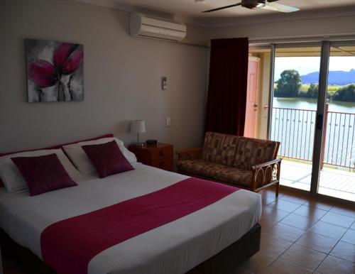 Tweed River Motel في مورويلومبا: غرفة نوم بسرير وكرسي ونافذة