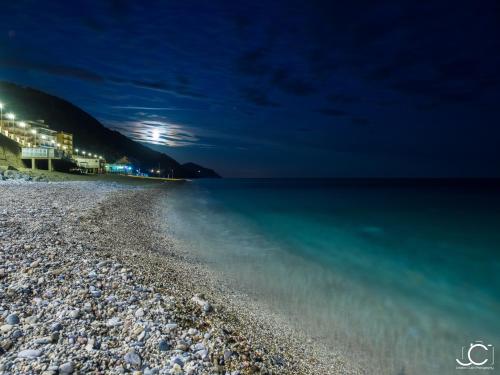 a beach at night with the moon in the sky at Appartamenti In Piazzetta in Deiva Marina