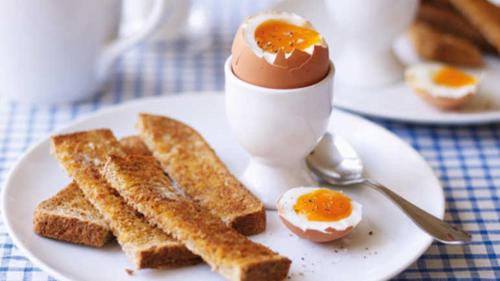 un piatto bianco con uova e pane tostato su un tavolo di 118 Shepherds Lane a Dartford