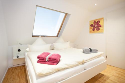 a bedroom with a white bed with pink towels on it at Residenz zum Südstrand/Levke in Borkum