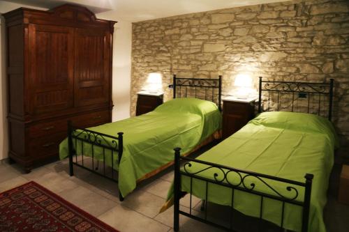 a bedroom with two beds and a stone wall at Casa Kuraj in Sestino