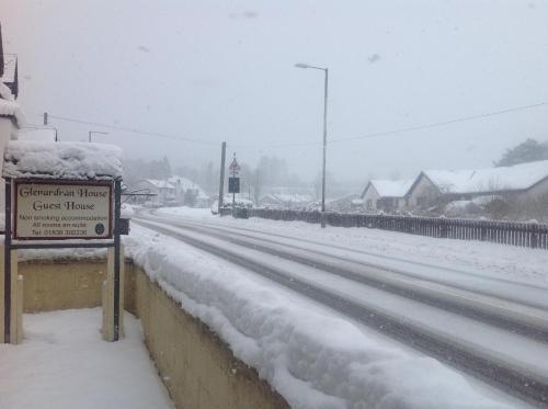 a road covered in snow with a sign on it at glenardran house in Crianlarich