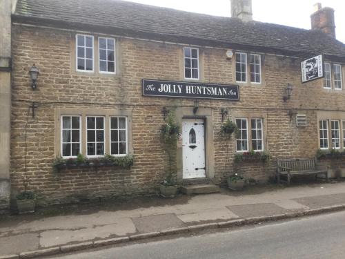 a brick building with a white door on a street at The Jolly Huntsman in Chippenham