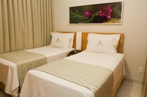 2 camas en una habitación de hotel con sábanas blancas en Ímpar Suítes Cidade Nova, en Belo Horizonte