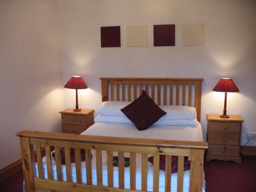 a bedroom with a wooden bed with two nightstands and two lamps at The Jolly Huntsman in Chippenham