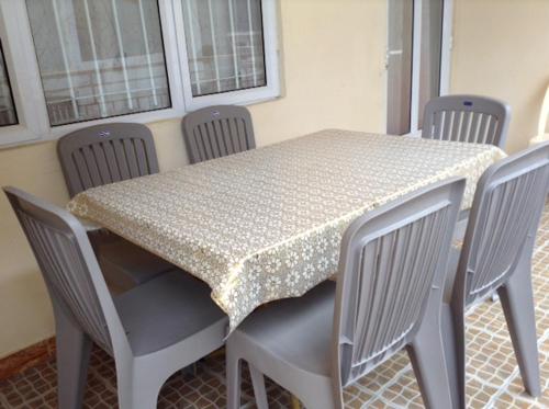 a dining room table with four chairs and a white table and chairsktop at Ebrahim Flats - Grand Baie Beach in Grand Baie