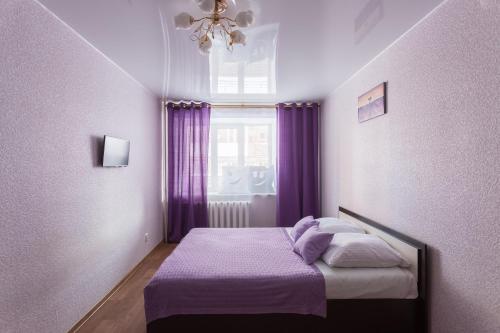 ヴォログダにあるApartment 2Pillows on Yuzhakovaのベッドルーム1室(紫色のカーテンと窓付きのベッド1台付)