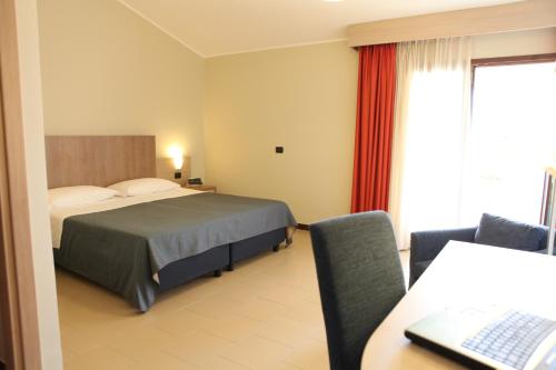 a hotel room with a bed and a desk with a computer at Heraclea Hotel Residence in Policoro