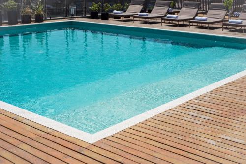 a swimming pool with chairs on a wooden deck at KOS Pilar Hotel in Pilar