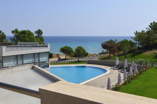a swimming pool with umbrellas and the ocean at Krotiri Resort in Agios Nikolaos
