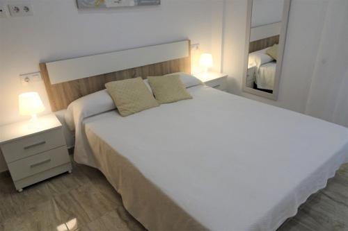 1 dormitorio con 1 cama blanca grande y espejo en Can Toni, en Porto Cristo