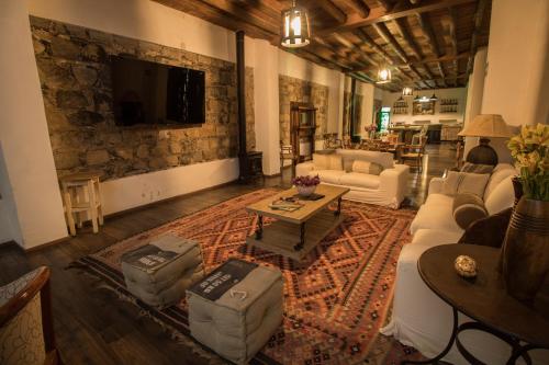 ein Wohnzimmer mit Sofas und einem TV an einer Steinmauer in der Unterkunft La Casona Del Banco Hotel Boutique in Parras de la Fuente