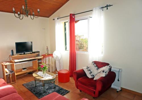 a living room with a red chair and a television at Villa Catanho in Funchal