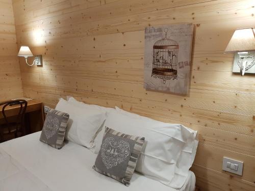 a bedroom with a bed with a wooden wall at Hotel Pedretti in Branzi