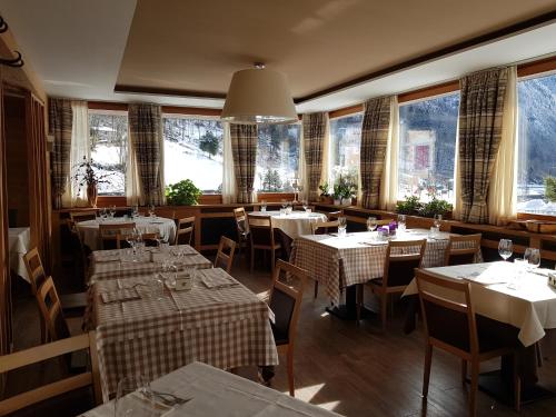 a restaurant with tables and chairs and large windows at Hotel Pedretti in Branzi
