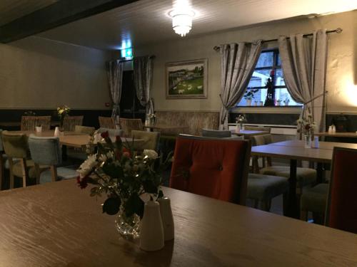 a restaurant with tables and chairs and a vase of flowers on a table at Grangegeeth Inn in Slane