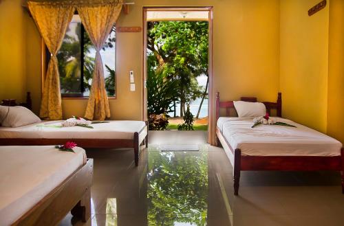 a room with two beds in a room with a window at Hotel Rancho Corcovado in Drake