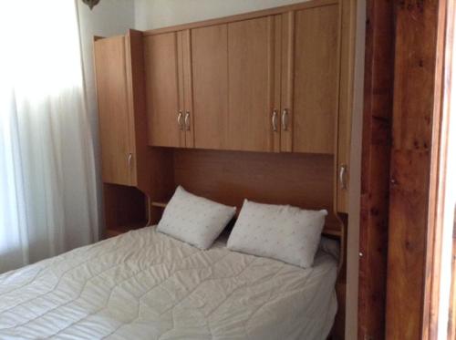 1 cama con 2 almohadas blancas y armarios de madera en Appartement Taghazout, en Taghazout