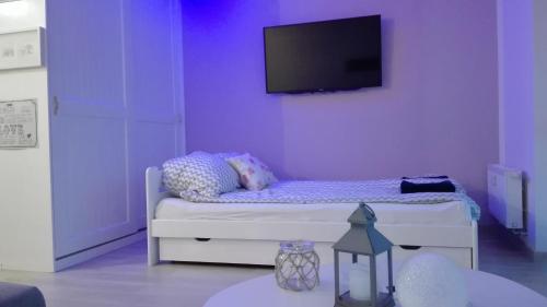 a purple room with a bed with a tv on the wall at Apartament Lux Monika Rewal z tarasem i garażem in Rewal