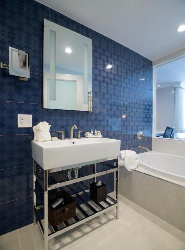 a bathroom with a sink and a tub and a mirror at Woodcrest Hotel Cupertino in Santa Clara