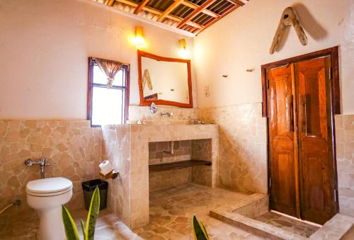 a bathroom with a toilet and a sink and a mirror at Amatoa Resort in Bira