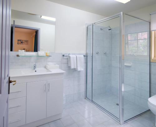 a white bathroom with a glass shower and a sink at Riverview Boutique Motel in Nambucca Heads
