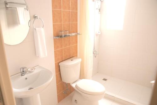 a bathroom with a toilet and a sink and a shower at M Suites Hotel in Manila