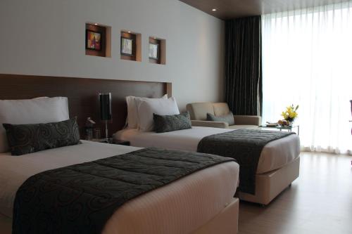a hotel room with two beds and a couch at Ramada by Wyndham Navi Mumbai in Navi Mumbai