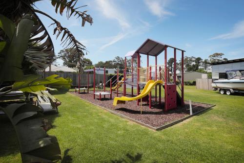 a playground with a slide on the grass at Georges Bay Apartments in St Helens