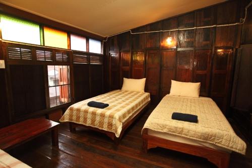 two beds in a room with wooden walls and windows at Baan Are Gong Riverside Homestay in Phra Nakhon Si Ayutthaya