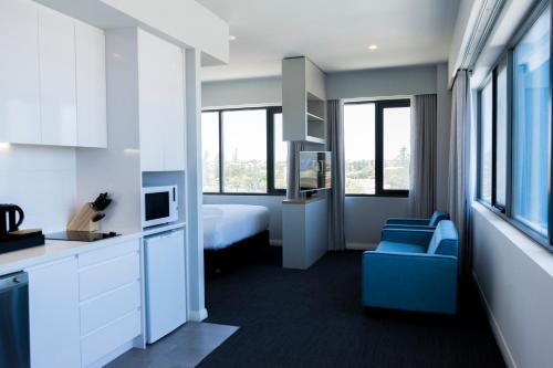 ein Hotelzimmer mit einem Bett und einem blauen Stuhl in der Unterkunft The Gerald Apartment Hotel in Geraldton
