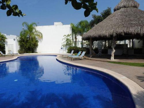 a large blue swimming pool with a straw hut at Nuevo Vallarta Casa Neptuno in Nuevo Vallarta